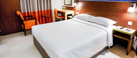 Una habitación de hotel con cama, escritorio, silla y mesita de noche.
