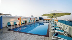 A rooftop pool with blue and white lounge chairs, a small bar area, and a city view. - Citymax Bur Dubai (Dubai)