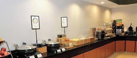 A buffet area with various food stations, including a hot pot and a fruit bowl.