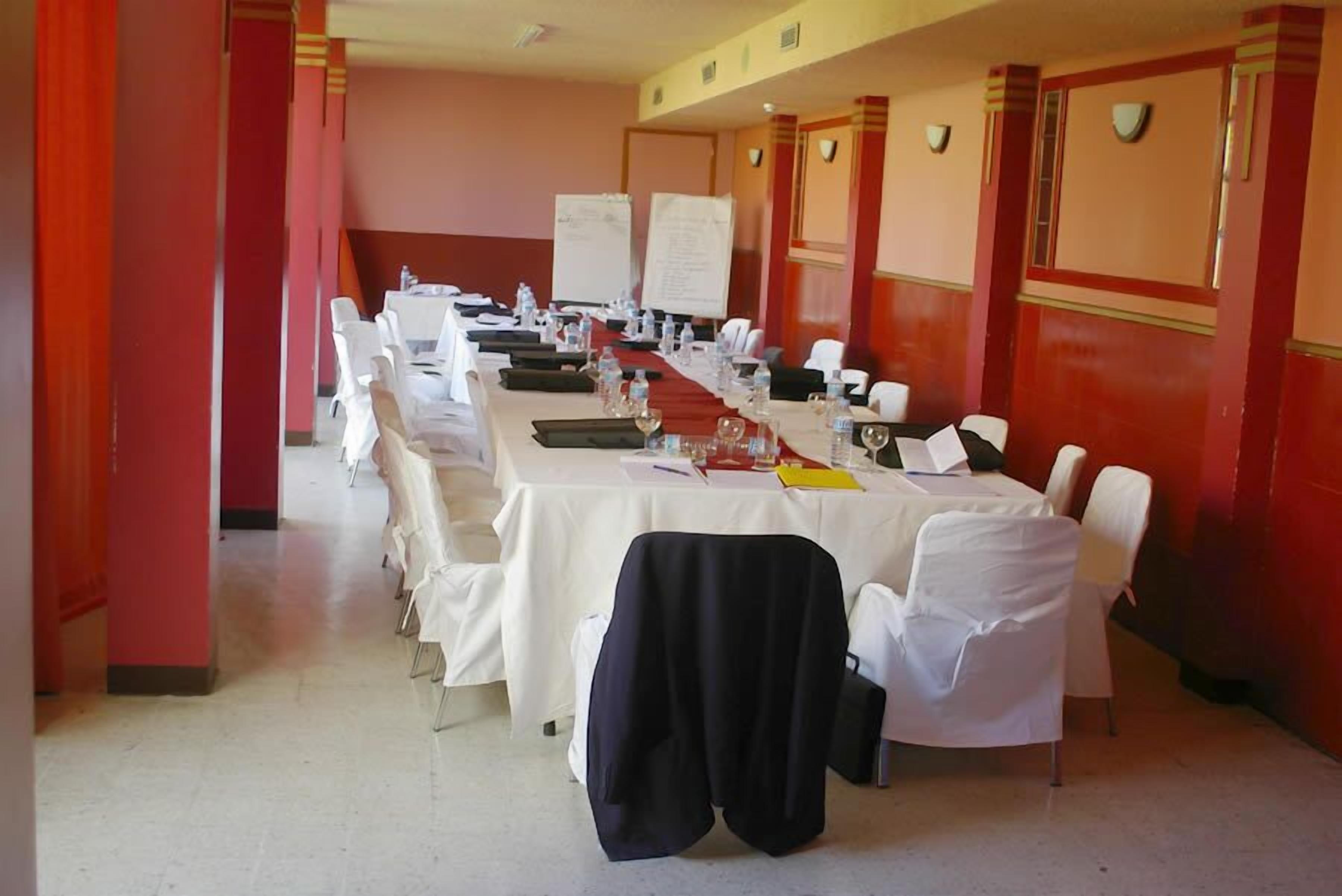 Una sala de conferencias con una larga mesa, sillas blancas y una pizarra.