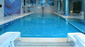 An indoor swimming pool with clear blue water, white lounge chairs, and modern lighting. - Nanjing New Century Hotel (Nanjing)