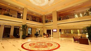 A spacious lobby with a large circular chandelier, multiple floors, and a central decorative carpet. - Nanjing New Century Hotel (Nanjing)