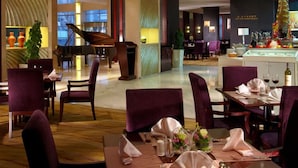 A restaurant with tables set for dining, a grand piano, and a bar area. - Nanjing New Century Hotel (Nanjing)