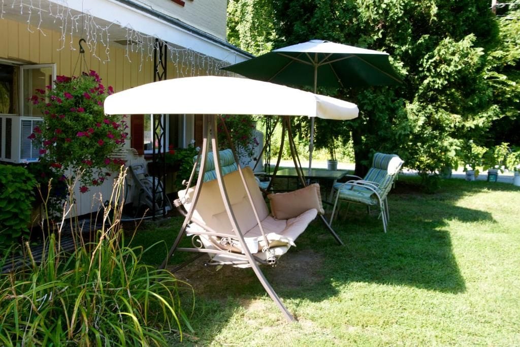 Une terrasse avec une chaise suspendue, une table et un parasol.
