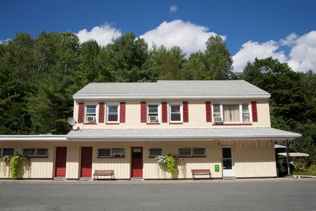 A two-story building with a flat roof, red shutters, and a front porch with benches.