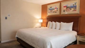 A hotel room with a large bed, a bedside table, a lamp, and two framed pictures on the wall.