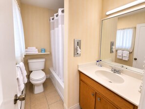 A bathroom with a toilet, bathtub, and a sink with a mirror.