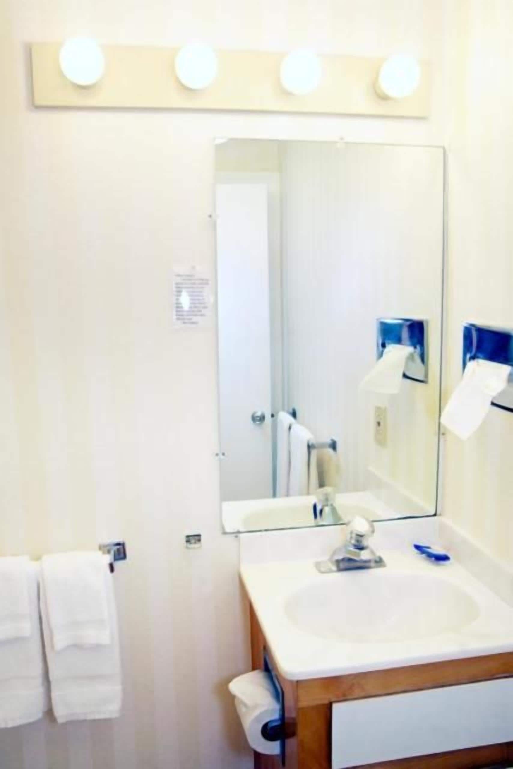 A bathroom with a sink, mirror, and towel rack.