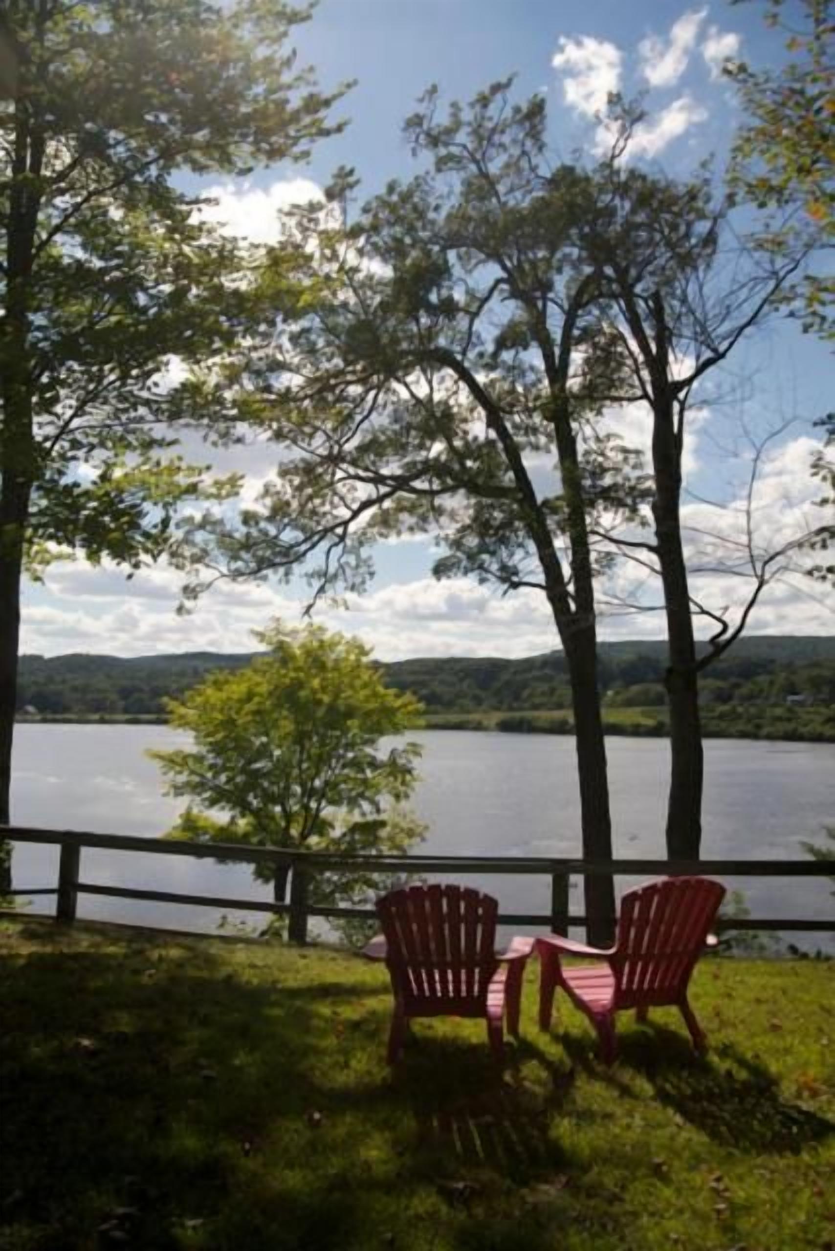 Vista del lago con dos sillas Adirondack mirando al agua.