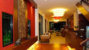Vestíbulo de hotel con suelo de madera, paredes rojas y un mostrador de recepción.