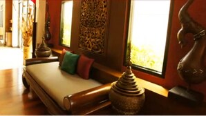 Una habitación con sofá, almohadones decorativos, una estatua y una ventana con vistas.