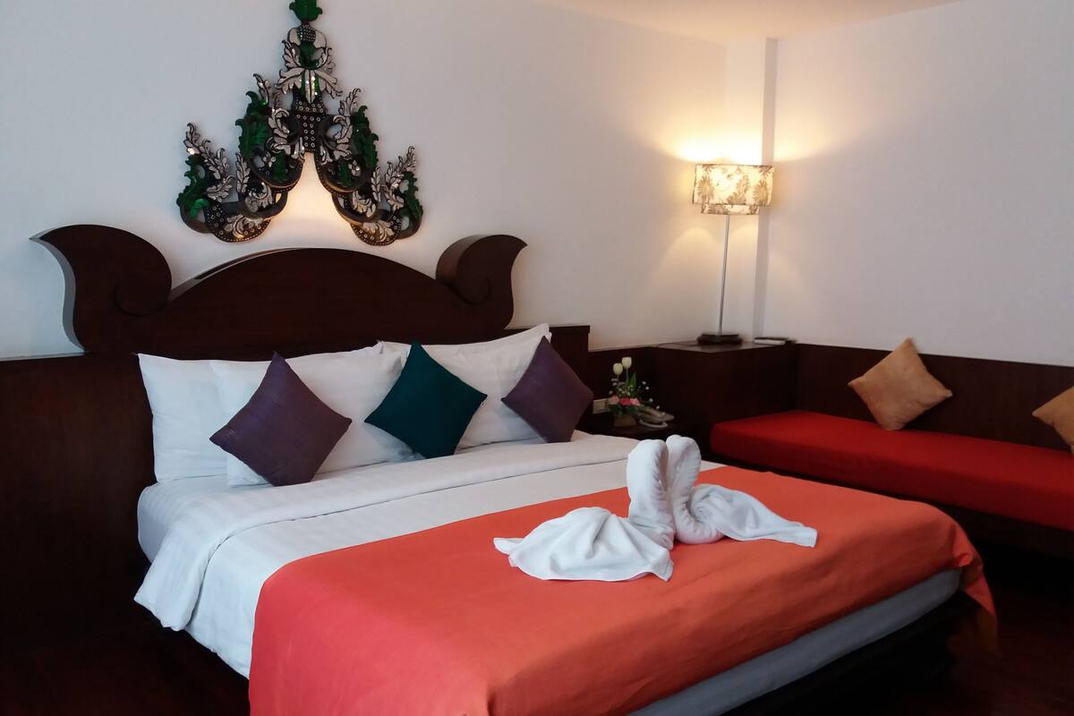 Une chambre d’hôtel avec un grand lit, une table de chevet, une lampe et un élément décoratif mural.