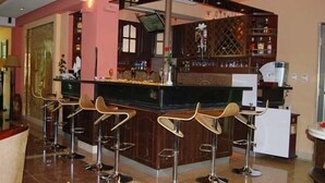 Een bar met een toog, krukken en een wijnrek.