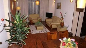 Een woonkamer met een bank, een salontafel, een televisie en een potplant.