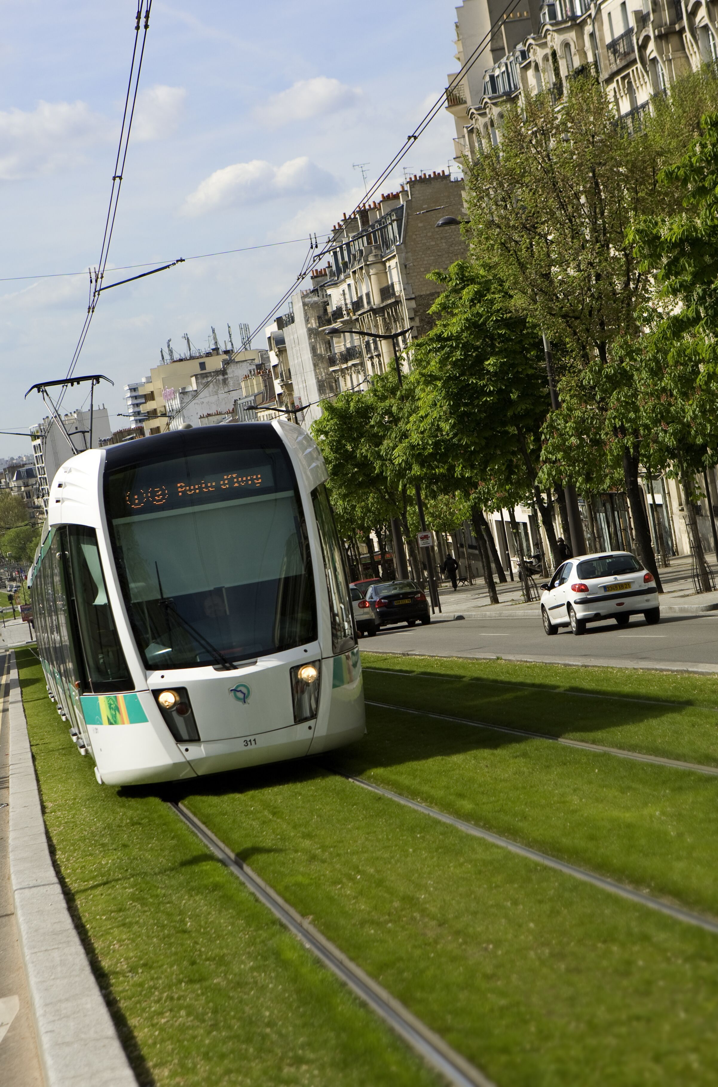 A tram on tracks with buildings and trees in the background.