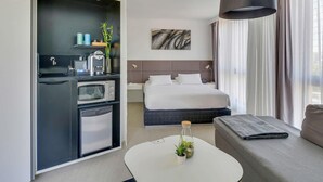 Une chambre d’hôtel moderne équipée d’une kitchenette, d’un lit, d’un canapé et d’une table à manger.