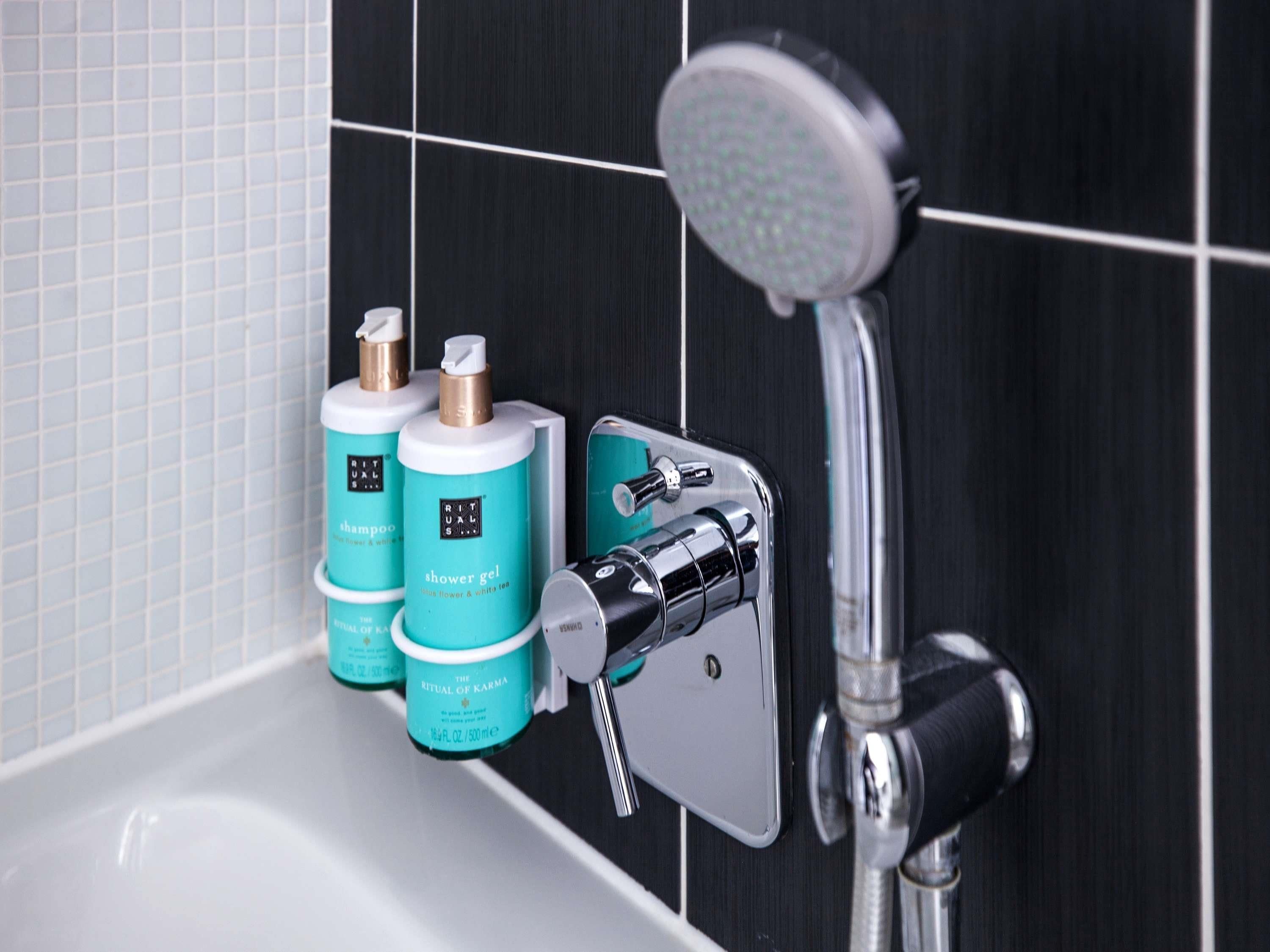 Une salle de bain avec une douche, un lavabo et deux bouteilles de gel douche de la gamme Ritual of Karma.