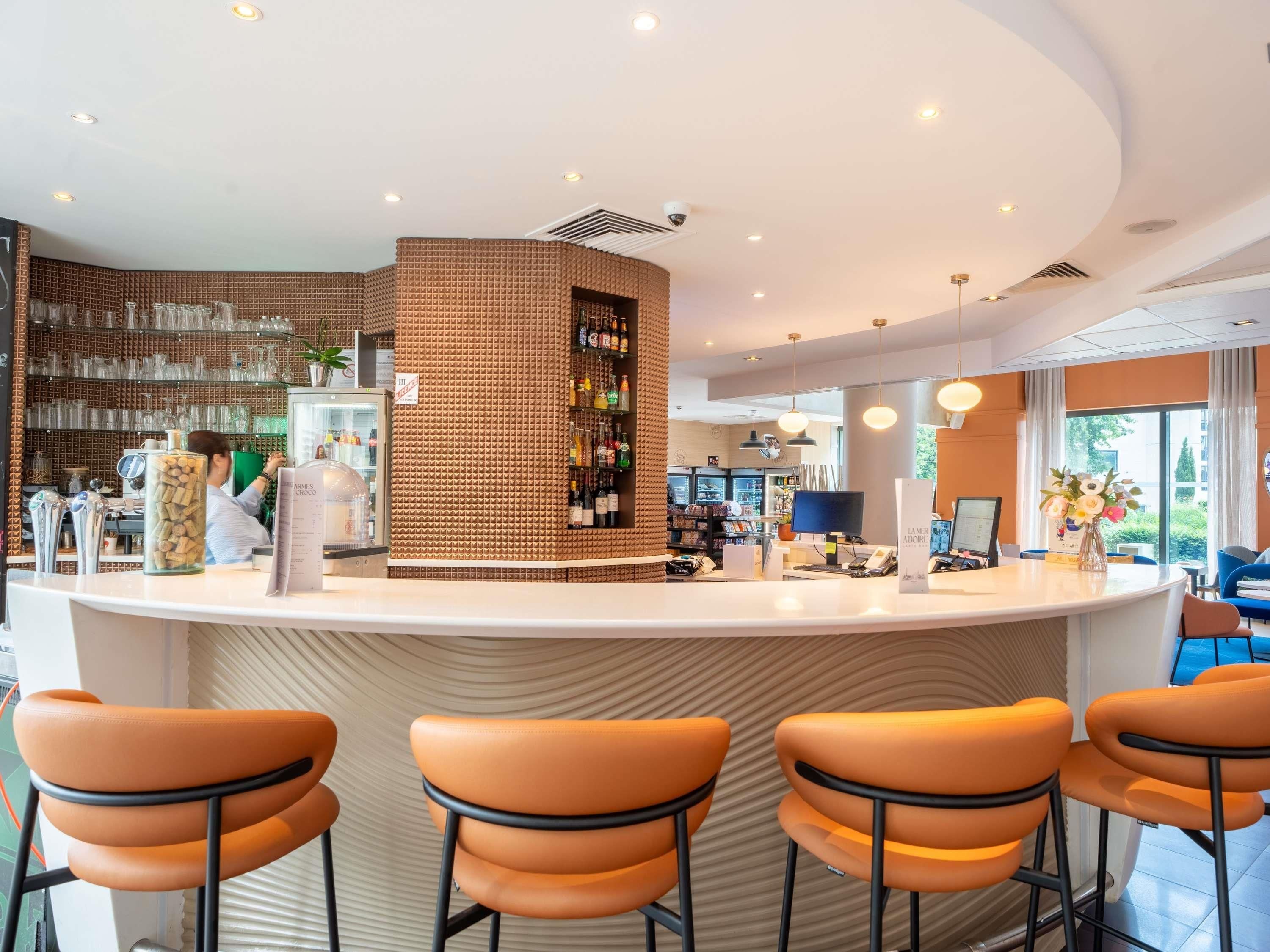 Un área de bar moderna con una barra curva, taburetes y una variedad de botellas.