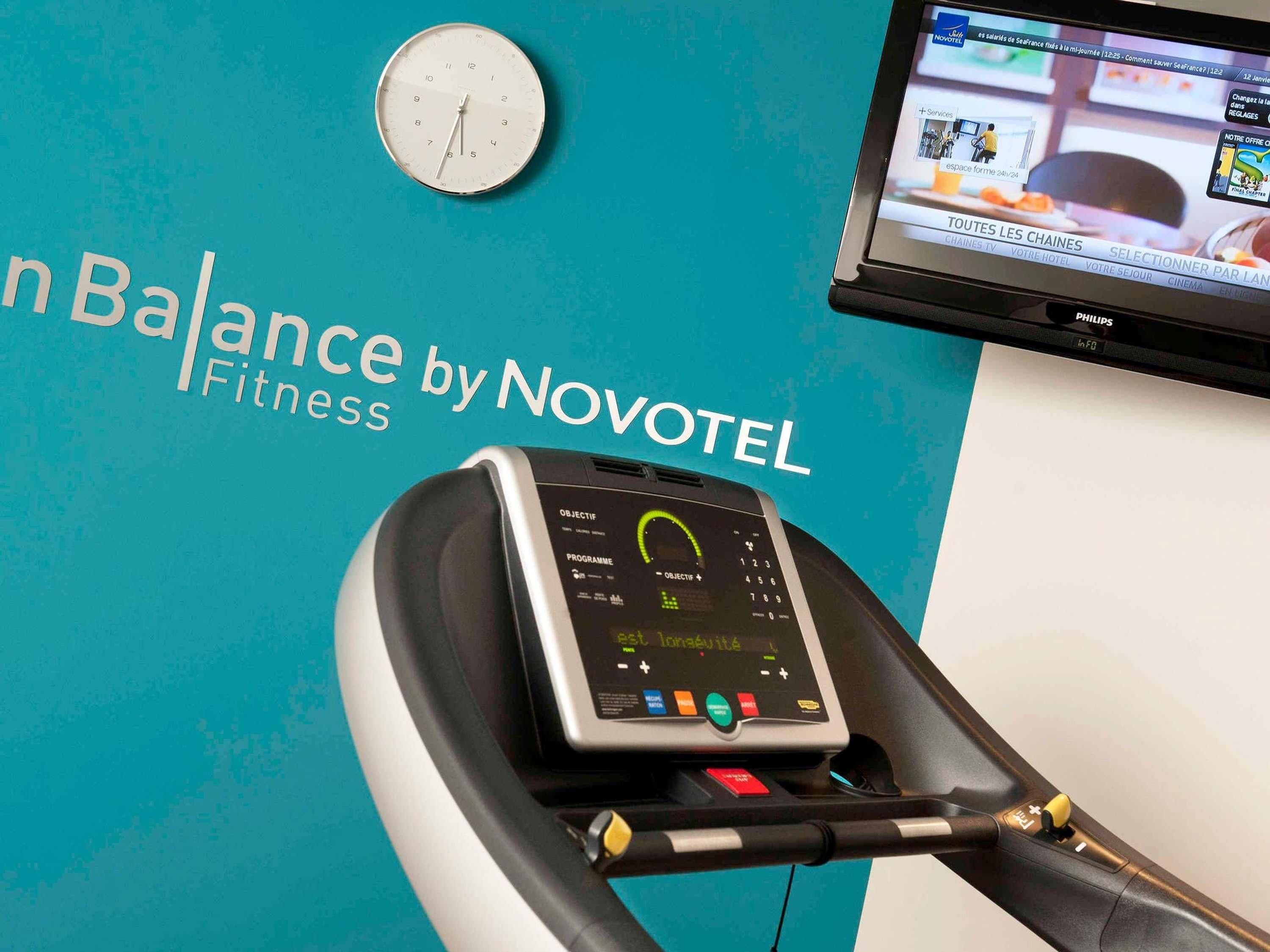 A fitness machine with a digital display and a wall clock above it.