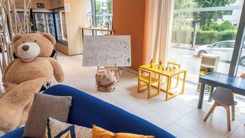 Relax in a warm and inviting space with a plush sofa, a large window offering a view of the street, and a small table with toys.