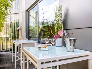 Une table en verre avec une bouteille de champagne, deux verres à vin et une petite assiette contenant de la nourriture.