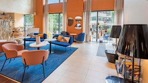 Eine moderne Hotelhalle mit einem großen Fenster, blauen Sofas, einem Teddybären und einer Lampenausstellung.