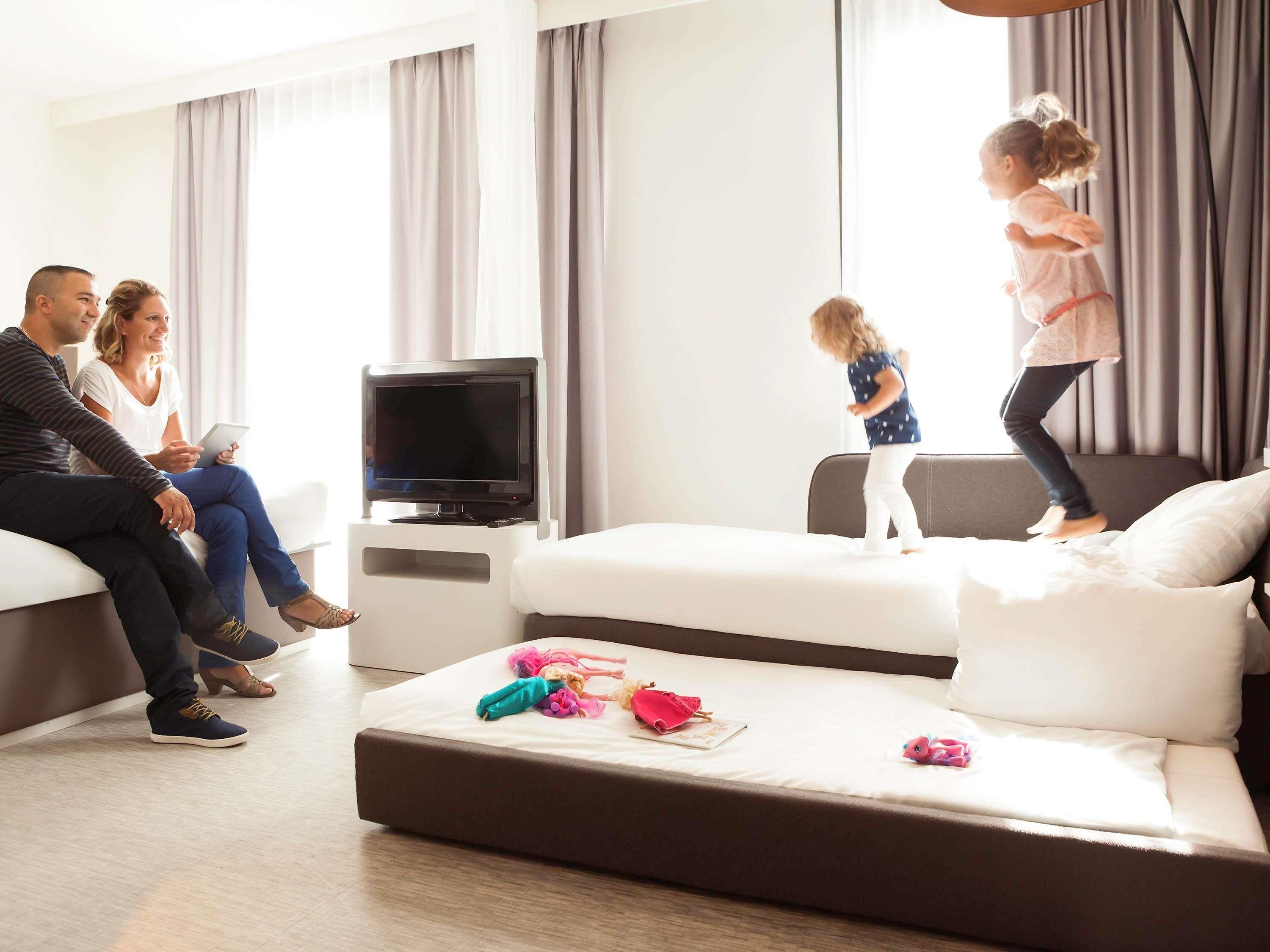 Ein modernes Wohnzimmer mit einer Couch, einem Fernseher und einem Kind, das auf dem Bett springt.