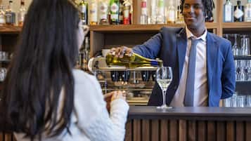 A bar setting with a bartender pouring a drink into a glass.