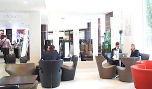 Un hall d'hôtel doté de mobilier moderne, d'un comptoir d'accueil et d'une enseigne « Novon » bien visible.