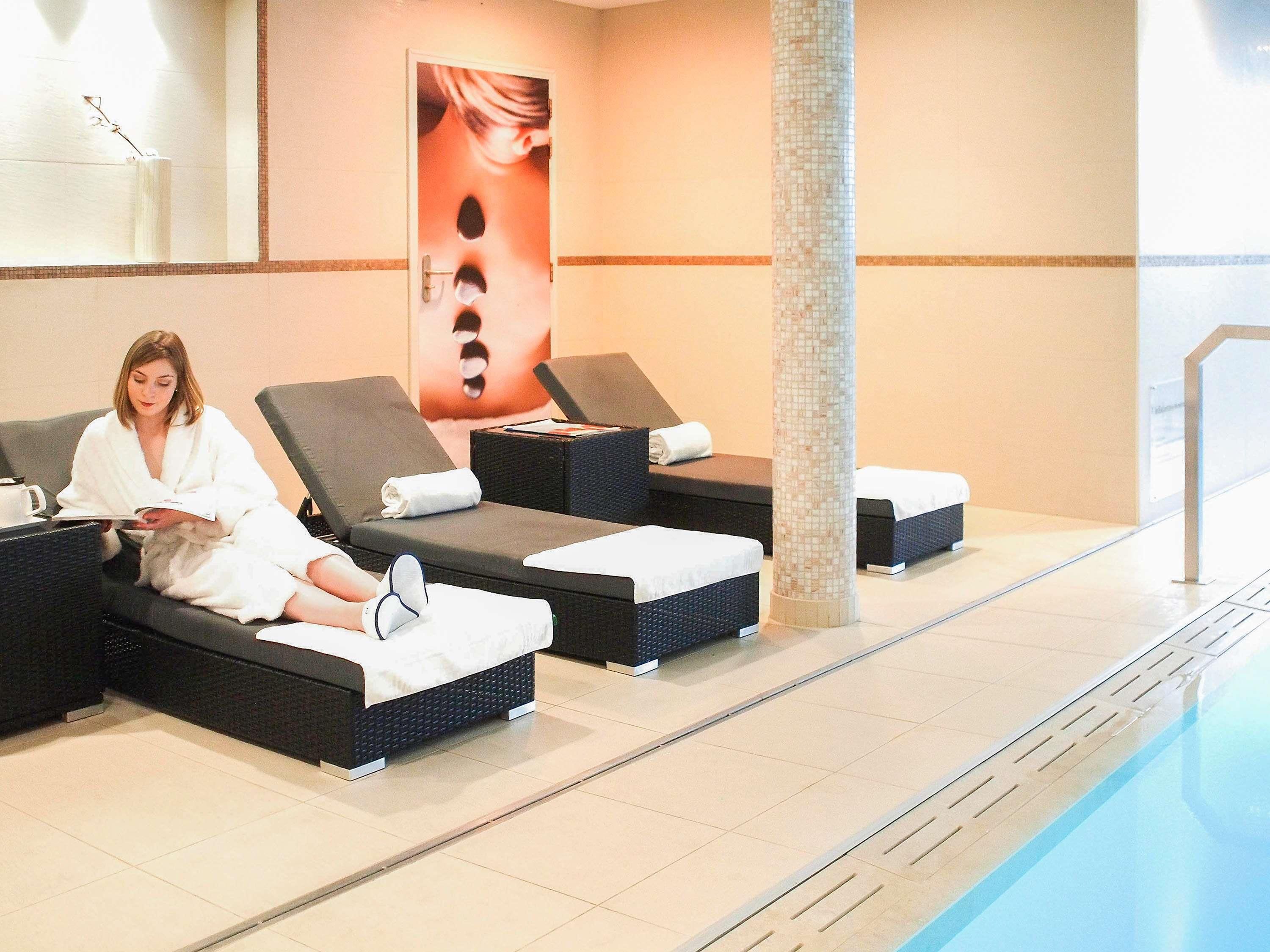 A spa area with reclining chairs, a tiled floor, and a pool.