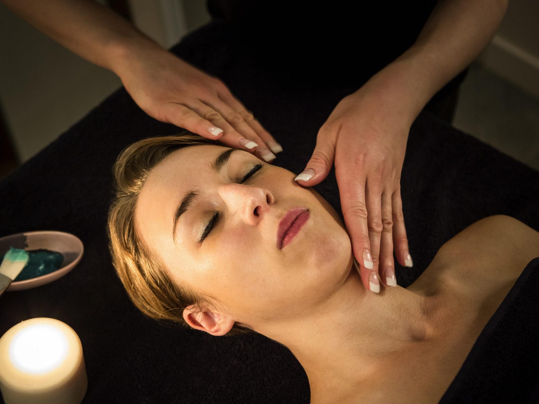 En person får massage där massören använder händerna på personens rygg. I närheten finns ett ljus och en skål med vad som ser ut att vara massageolja eller -kräm.