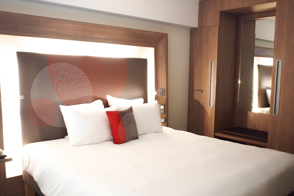Une chambre d’hôtel avec un grand lit, une armoire et un miroir.