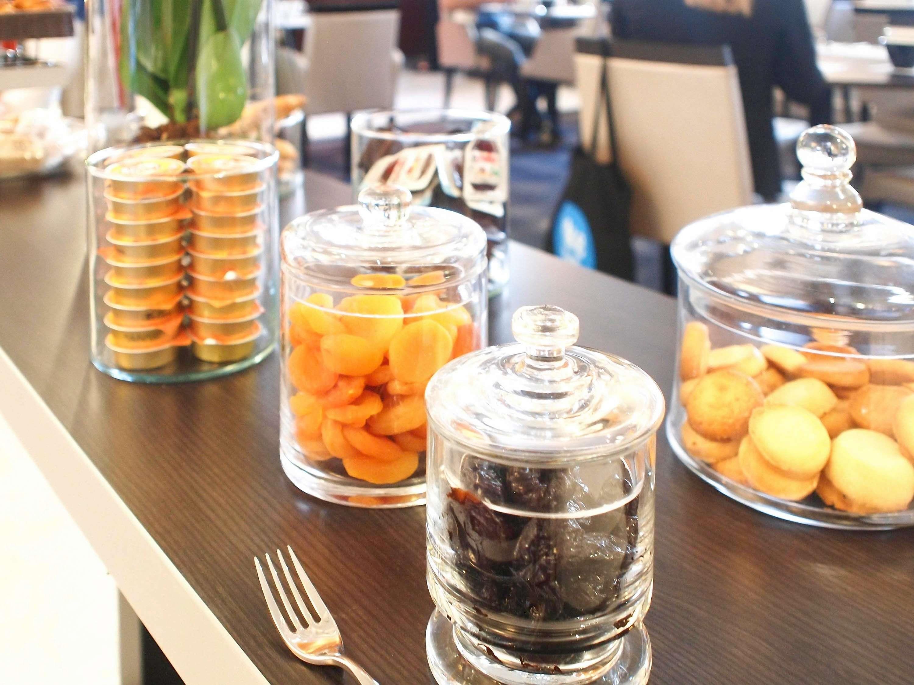 A buffet table with various food items in glass containers.