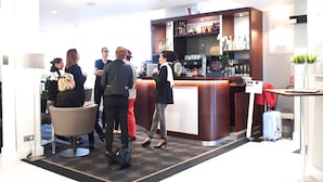 Un moderno vestíbulo de hotel con una zona de bar, asientos y un mostrador de recepción.