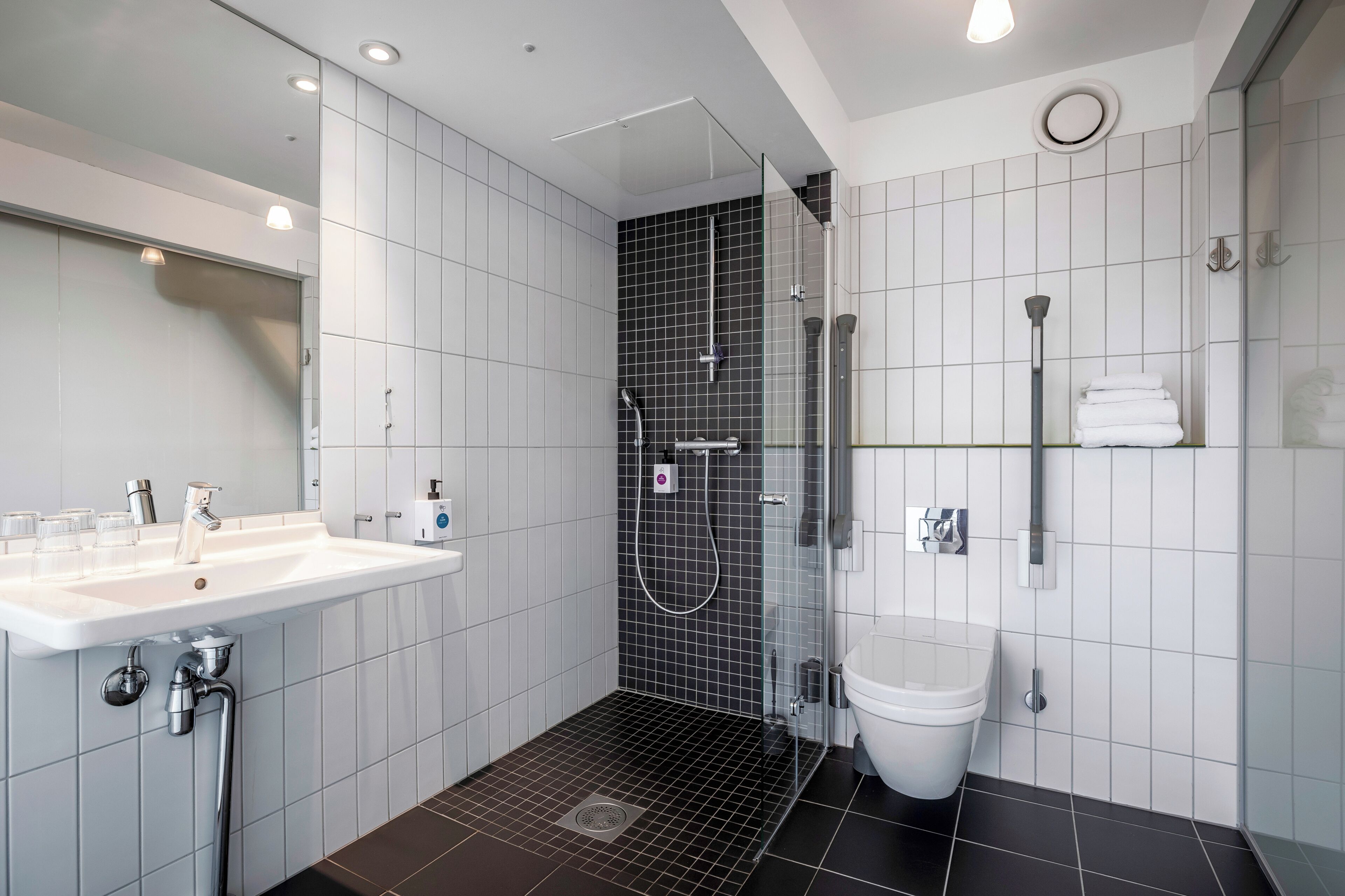 A modern bathroom with a shower, toilet, and sink.