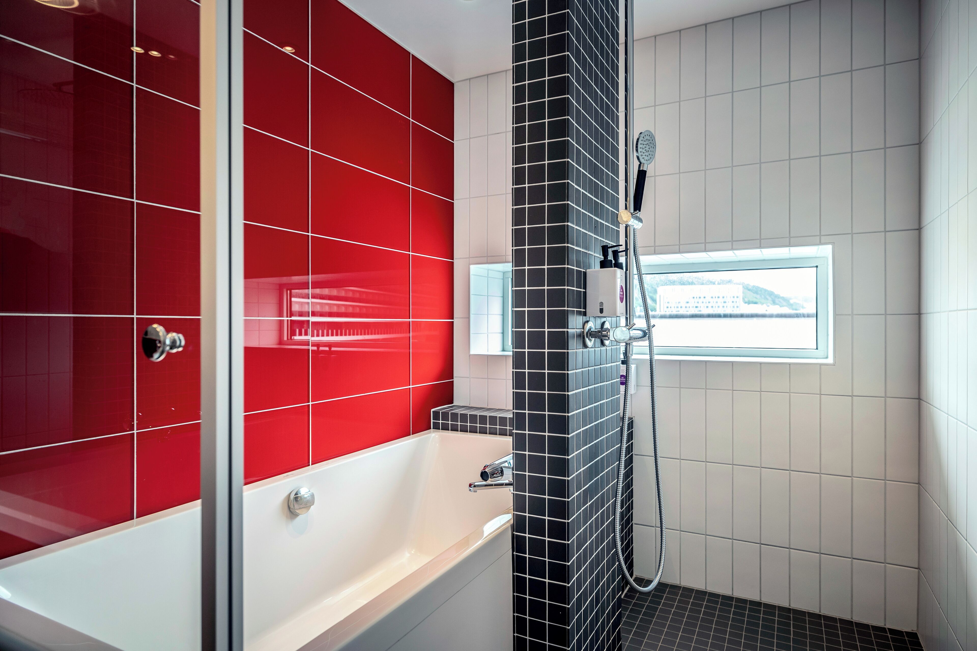 A modern bathroom with a bathtub, shower, and a window with a view.