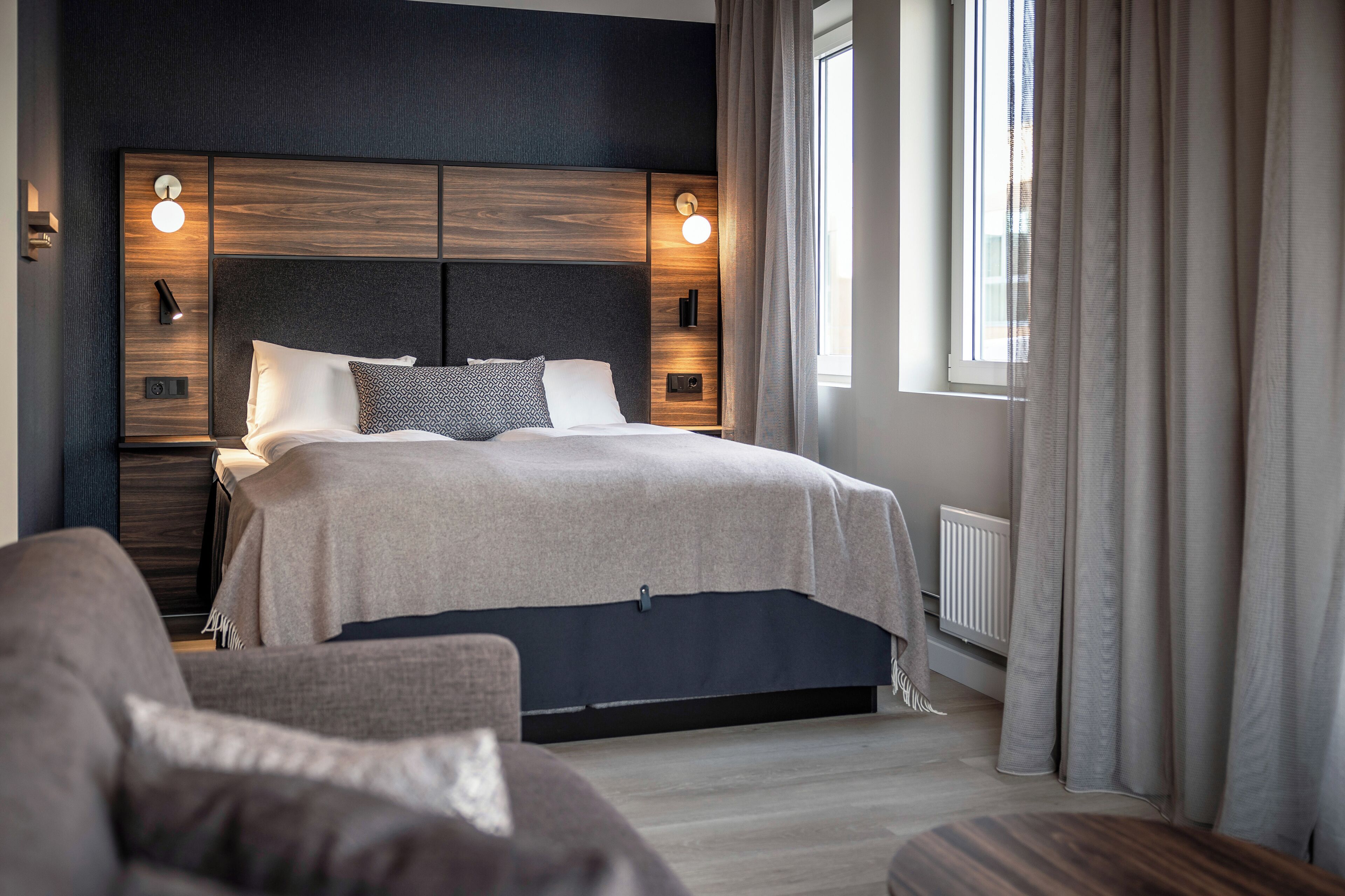 A modern bedroom with a bed, bedside tables, and a window with curtains.