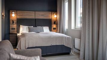 Un dormitorio moderno con cama, mesitas de noche y ventana con cortinas.