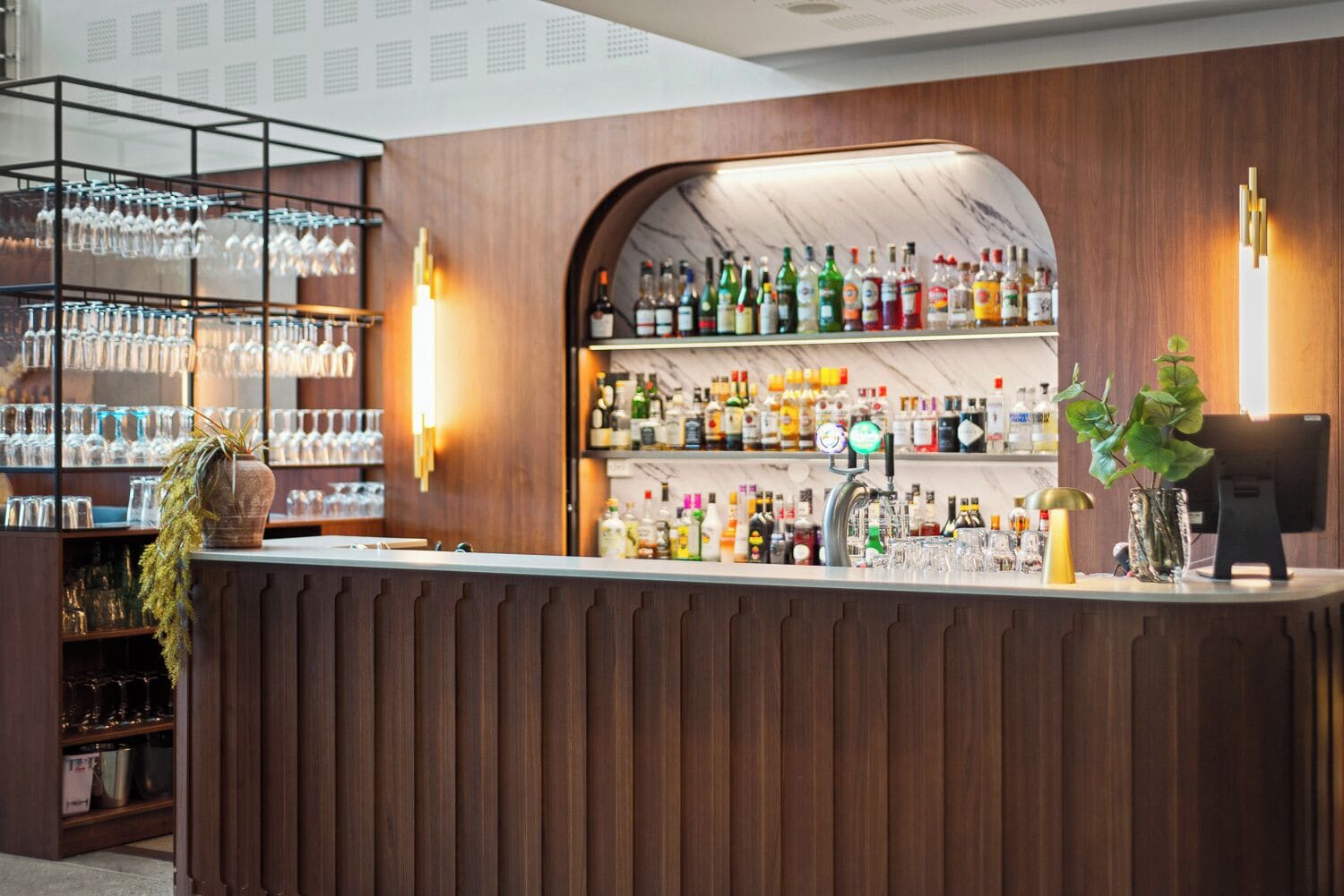 Eine Bar mit Holztresen, Regalen voller Spirituosenflaschen und einer Kasse.