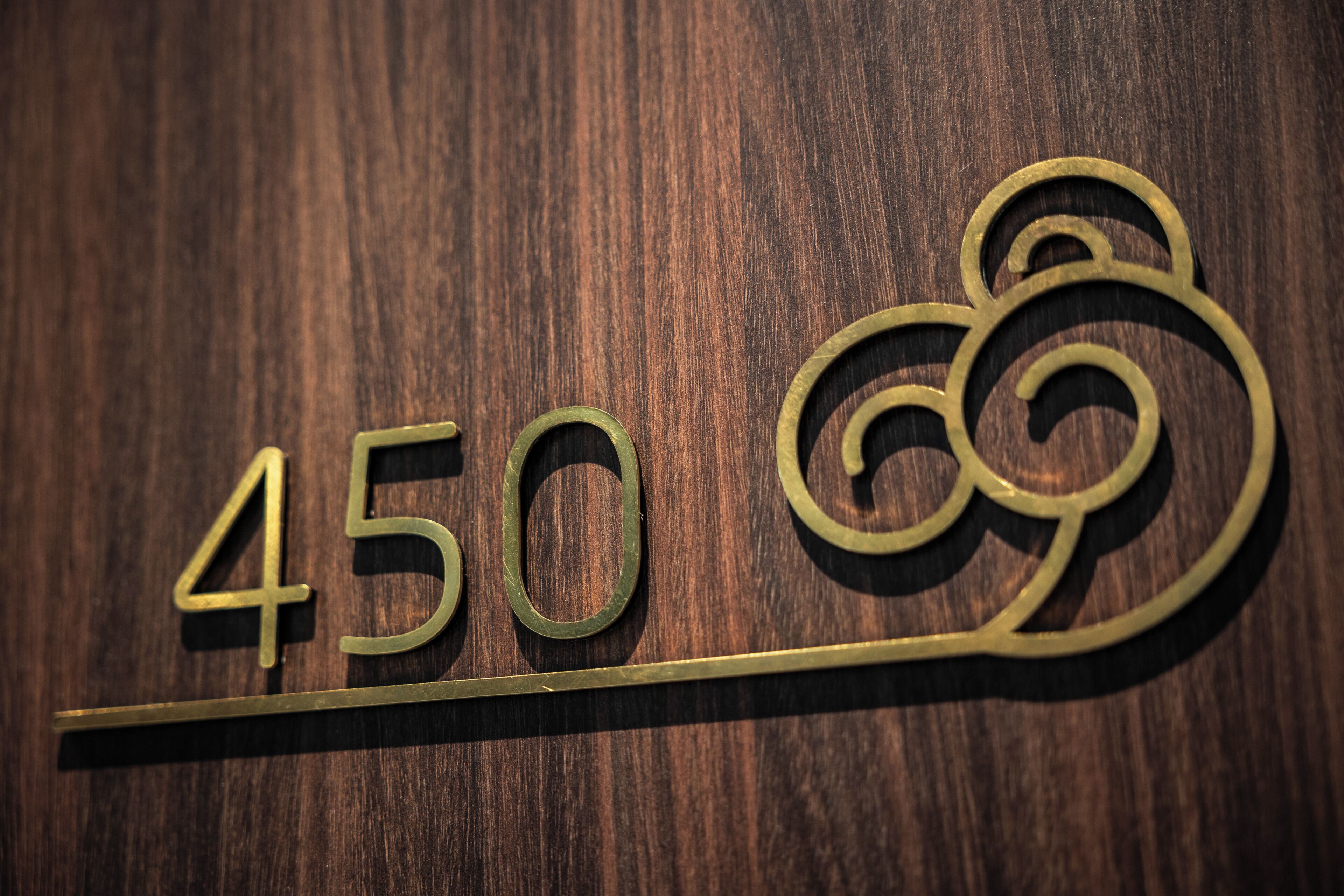 Superficie de madera con el número '450' en latón y un motivo ornamental de remolino.