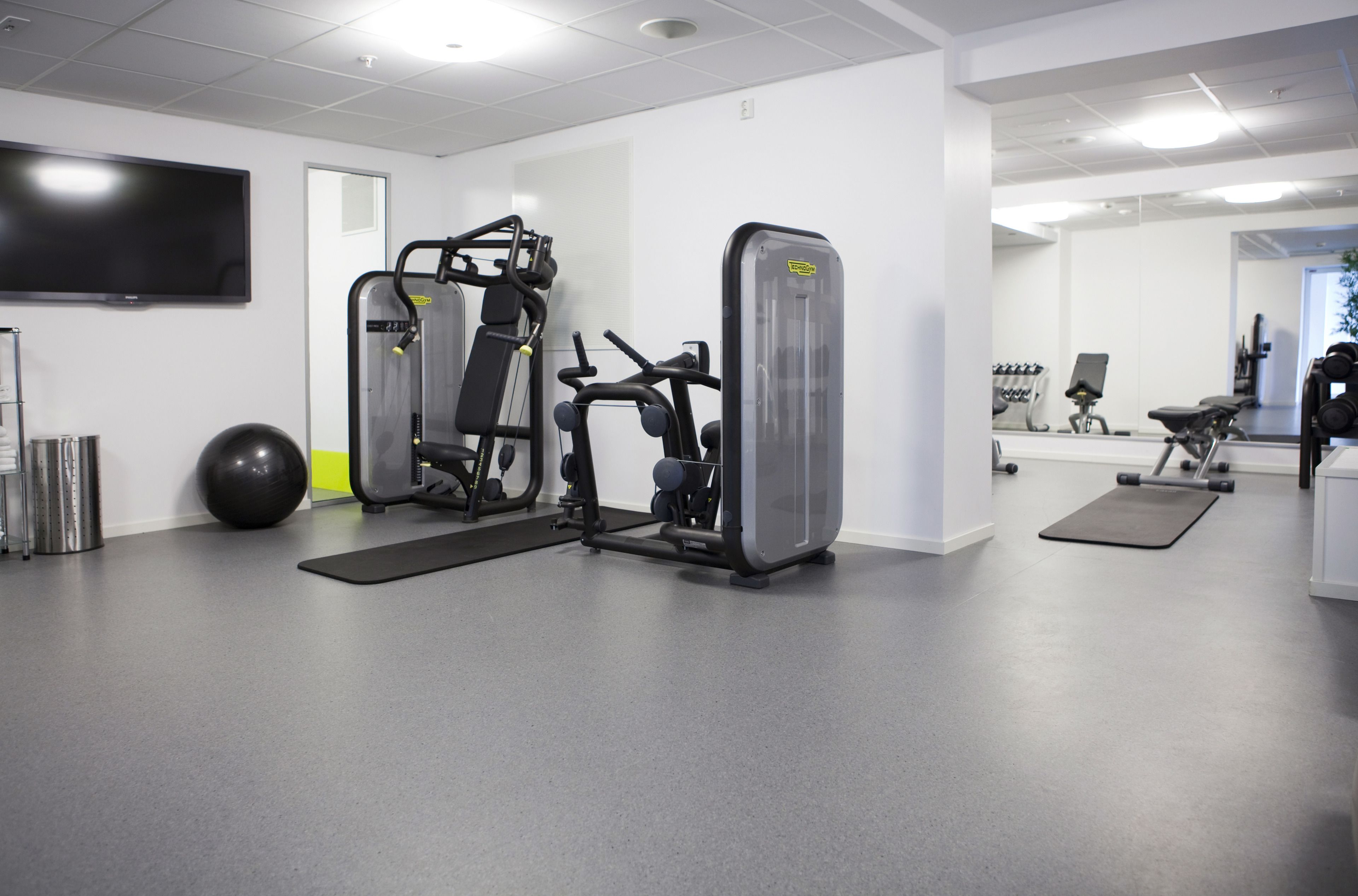 A gym with cardio machines, a stationary bike, and a mirrored wall.