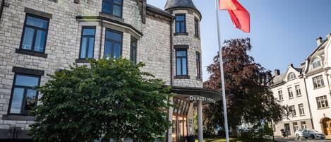 Un edificio de piedra con una torre, una bandera y un cartel que dice "Quality Hotel".