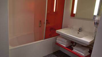 A bathroom with a shower, a sink, and a mirror.