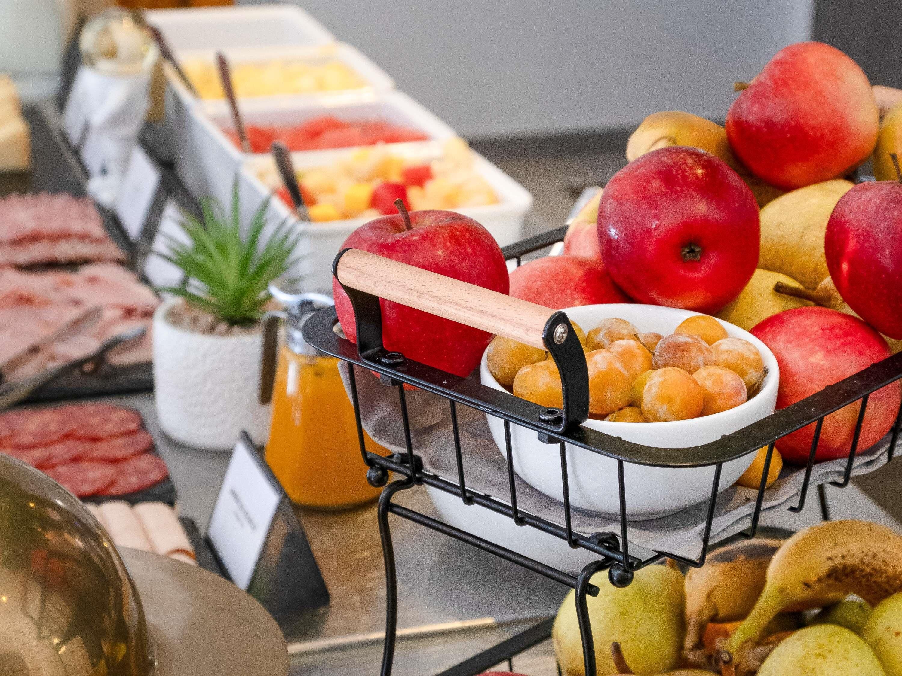 A buffet with various food items, including fruits and a bowl of pastries.