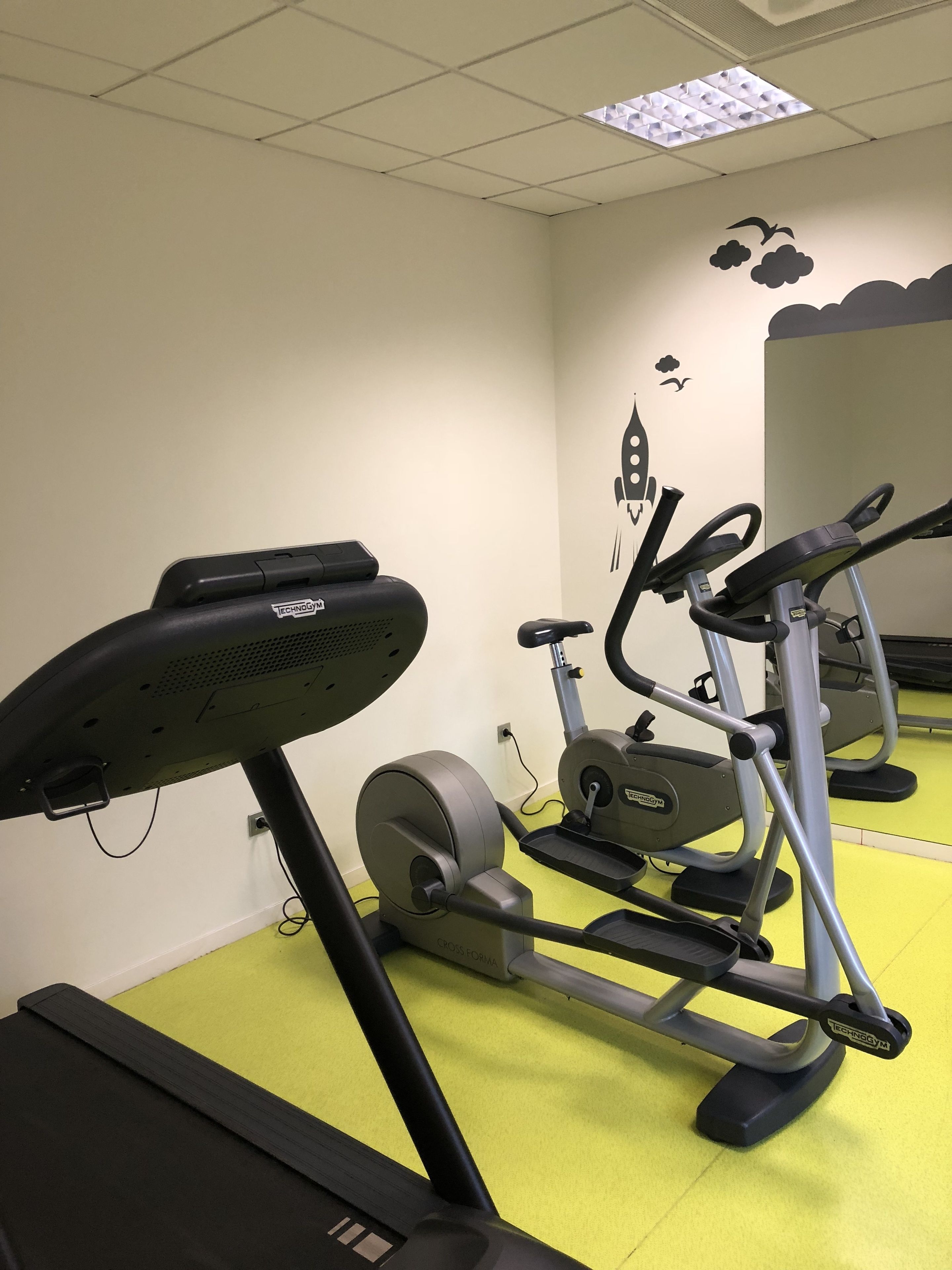 Ett gym med träningsutrustning, inklusive ett löpband och en crosstrainer.