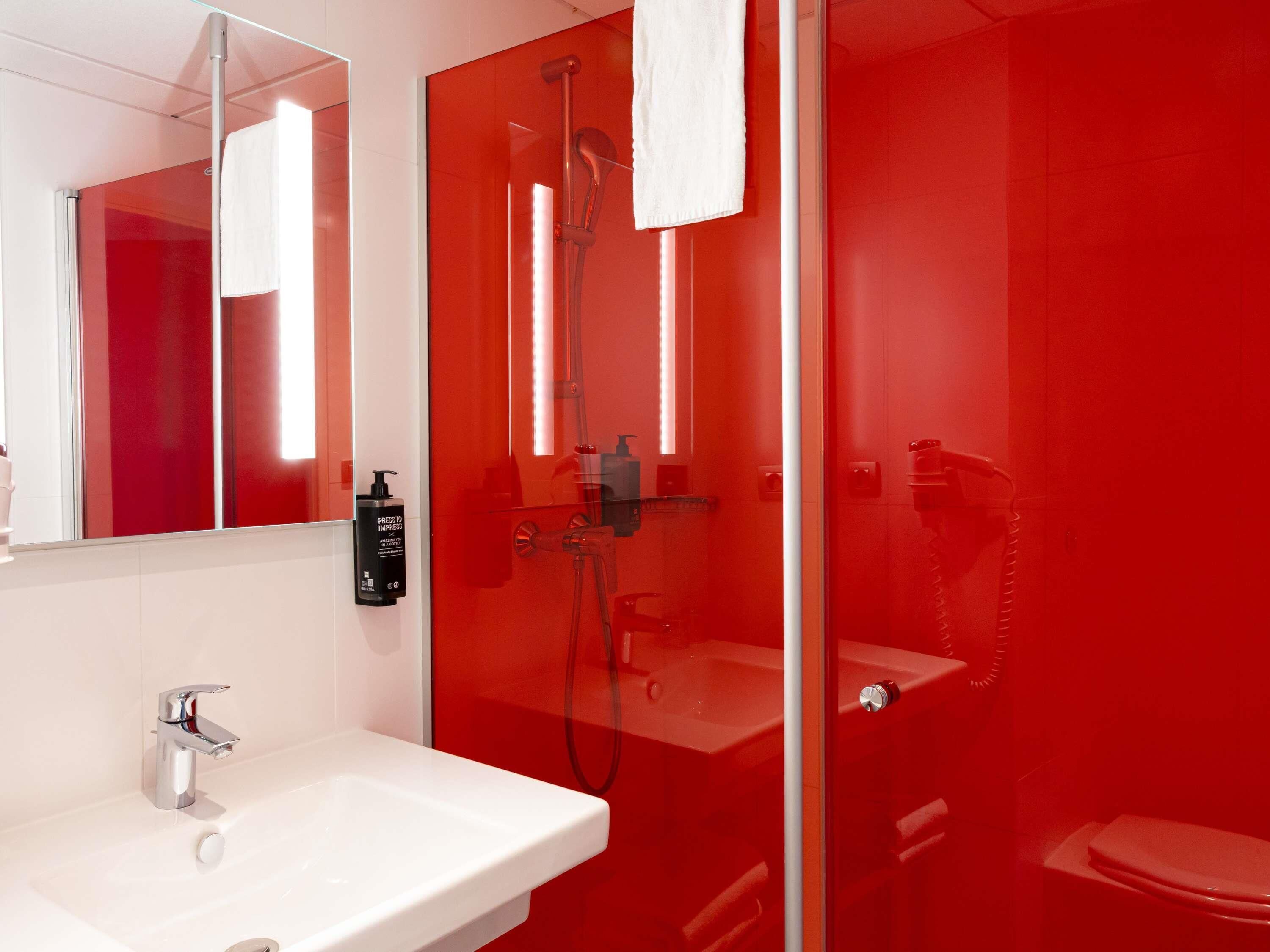 A modern bathroom with a glass-enclosed shower, a white sink, and a toilet.
