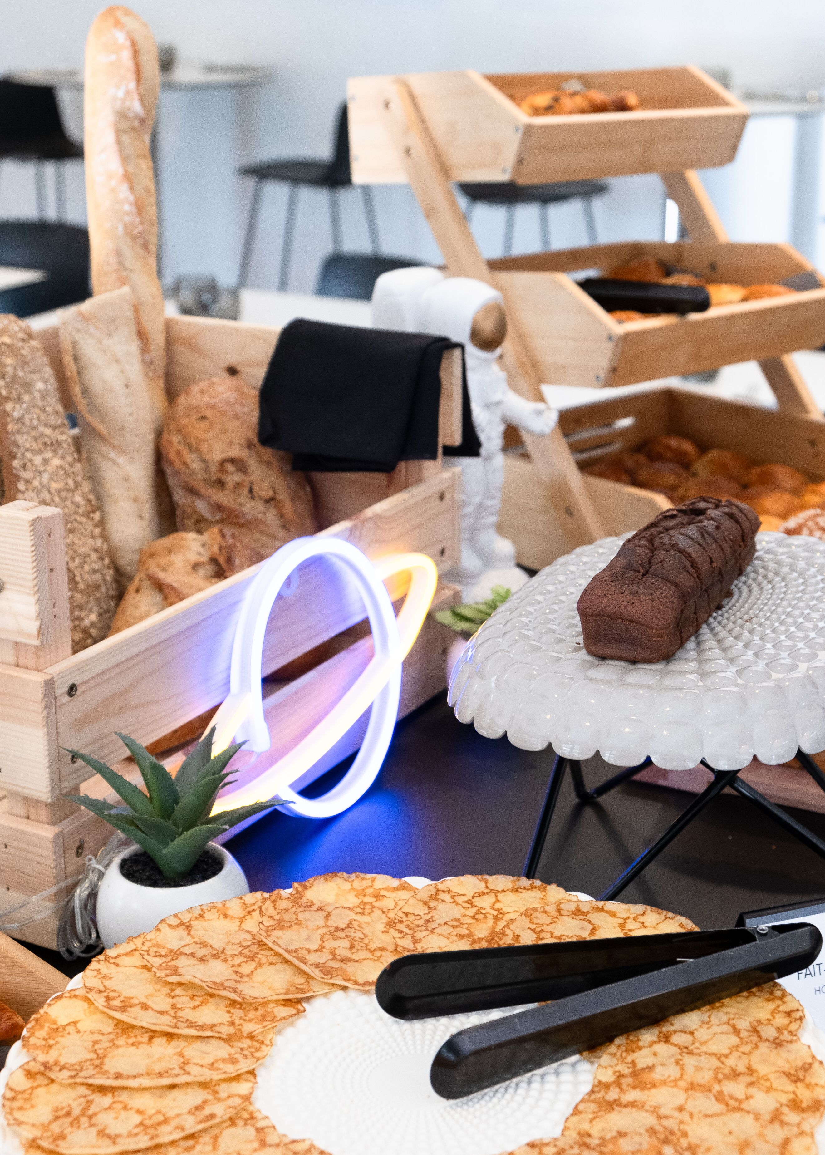 A variety of breads and pastries displayed on wooden stands and a white plate.