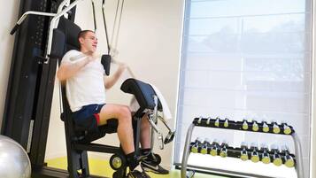 A gym with exercise equipment, a dumbbell rack, and a window with a view.