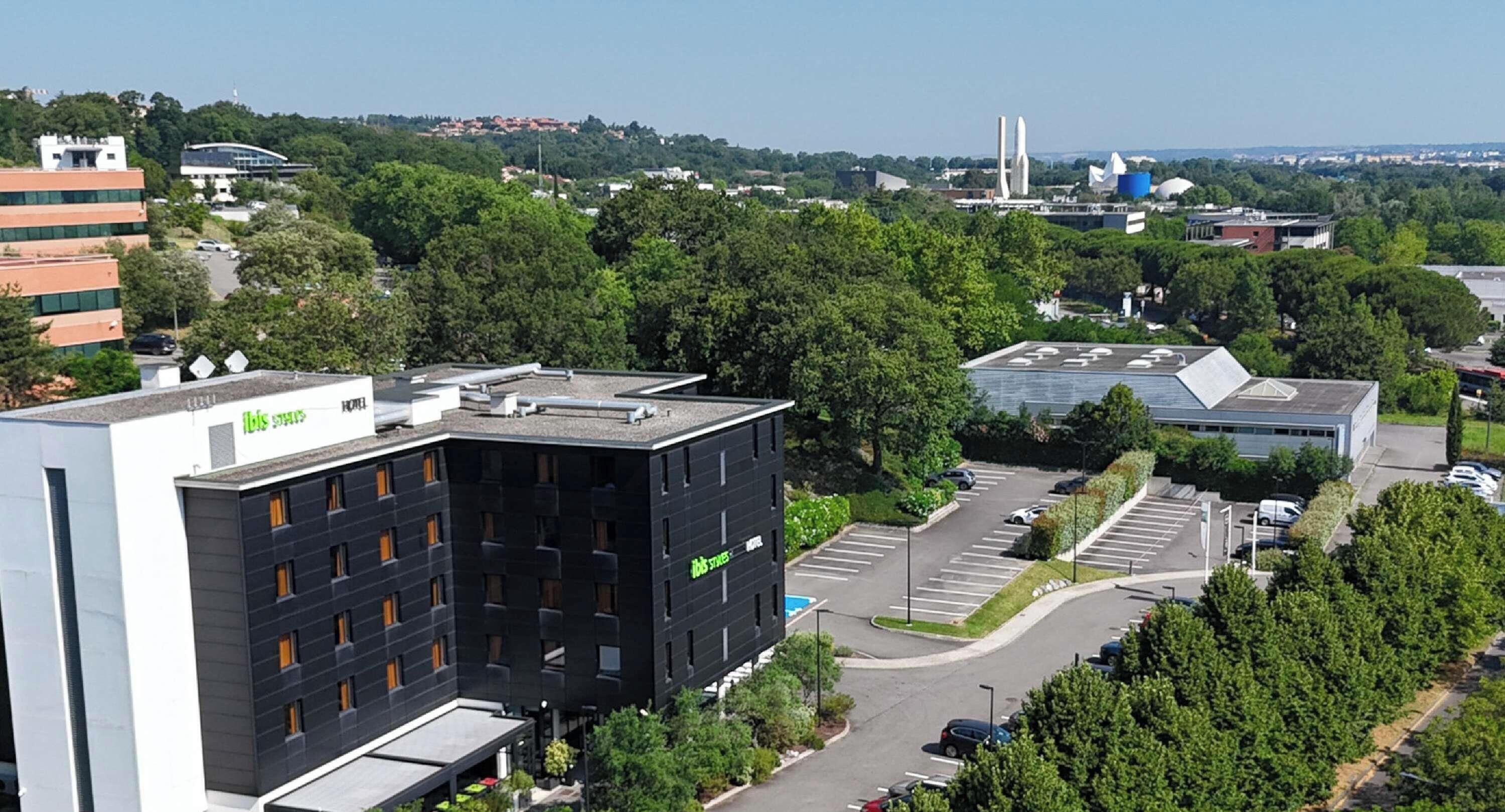 A modern building with a rooftop parking area and a green sign.