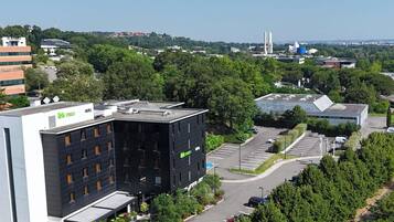 A modern building with a rooftop parking area and a green sign.